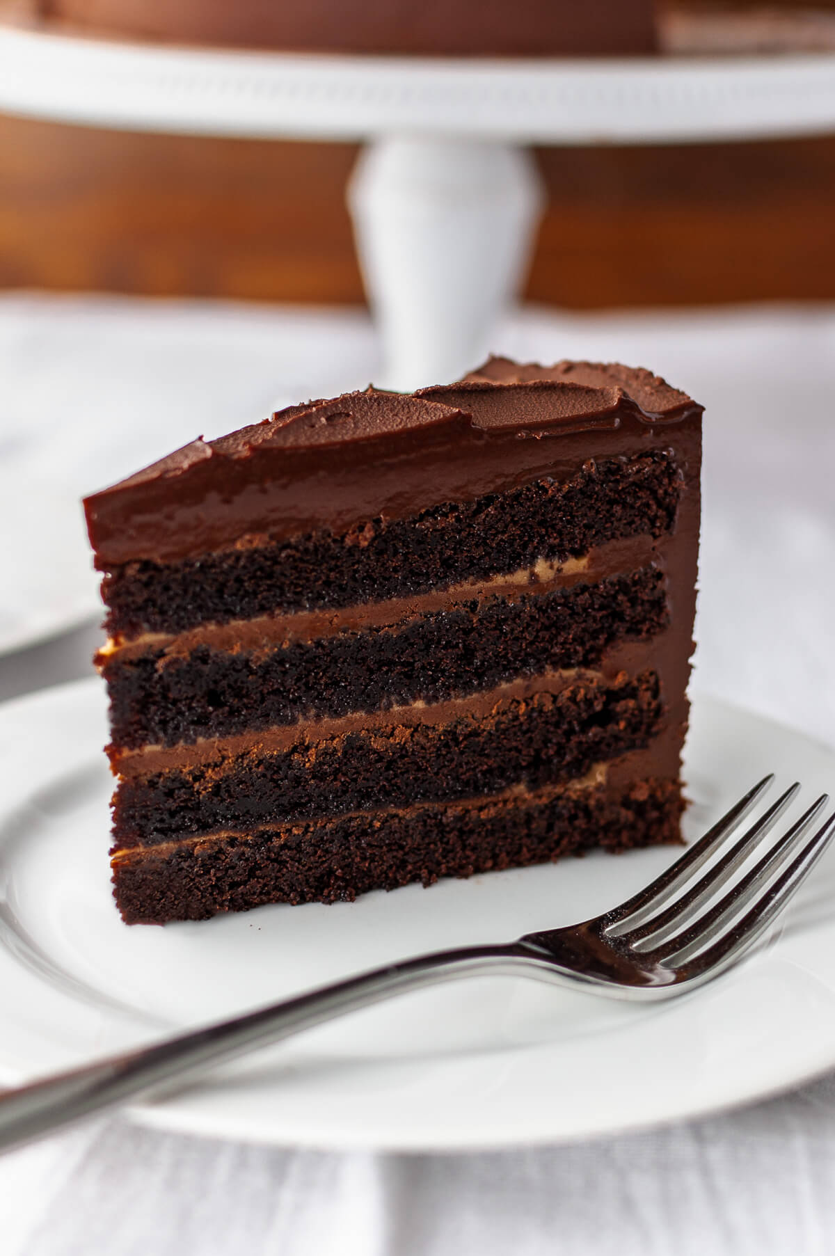 A slice of chocolate cake with caramel filling on a white plate.
