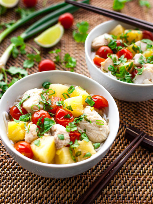 Two bowls of Vietnamese fish, pineapple, and tomato soup sprinkled with chopped green onions and cilantro.