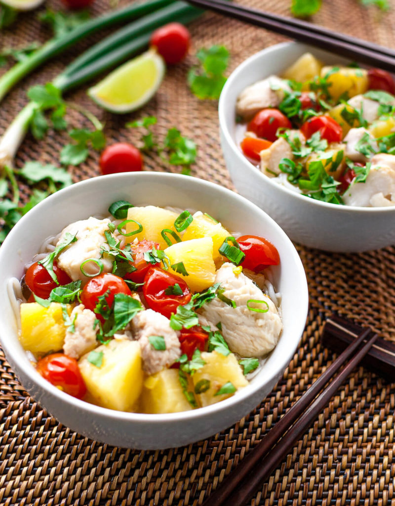 Two bowls of Vietnamese fish, pineapple, and tomato soup sprinkled with chopped green onions and cilantro.