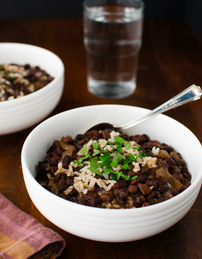 Two bowls of black bean soup with rice garnished with chopped cilantro.