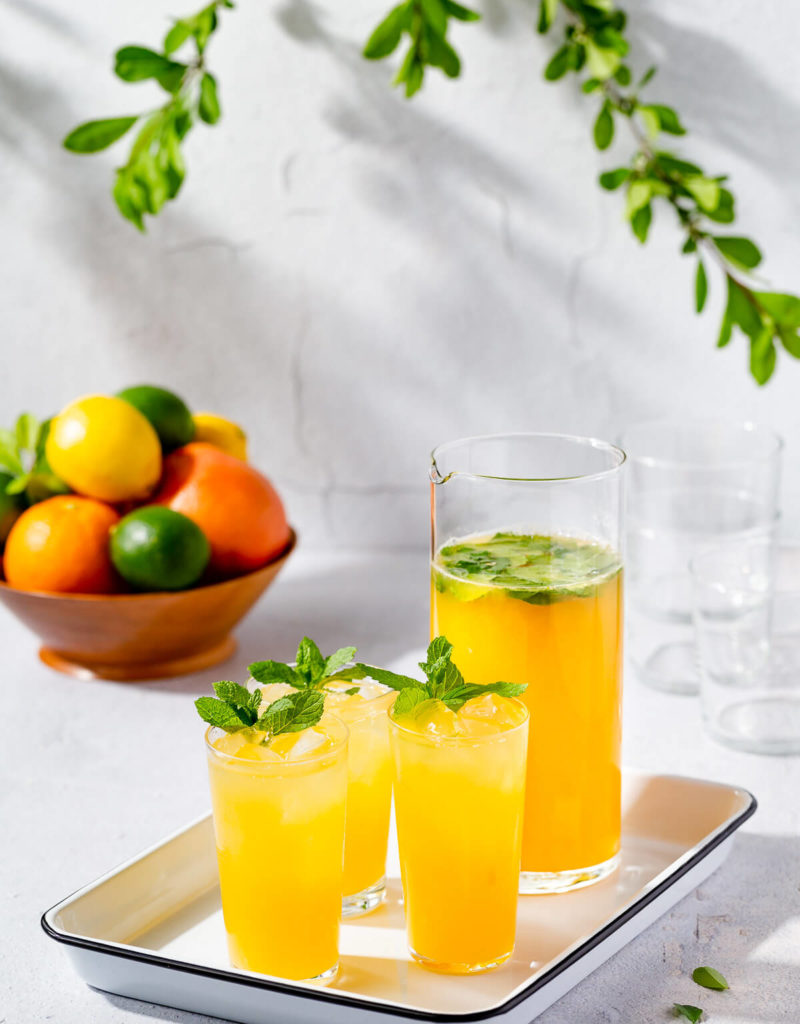 Three glasses and a pitcher of mintade on a white tray.