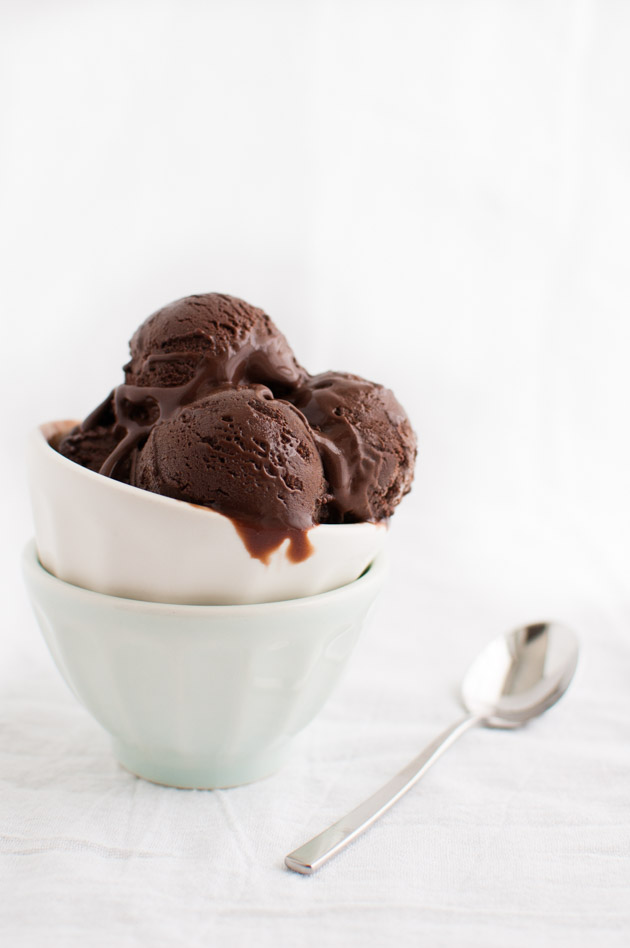 A small bowl of dark chocolate gelato next to a dessert spoon.
