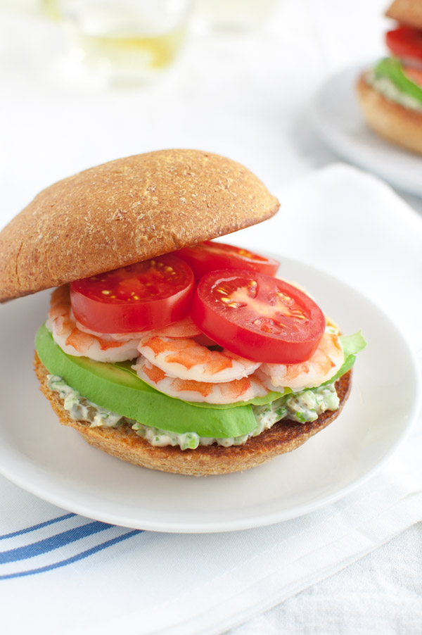 A shrimp sandwich with caper mayo, sliced avocado, shrimp, and tomatoes.