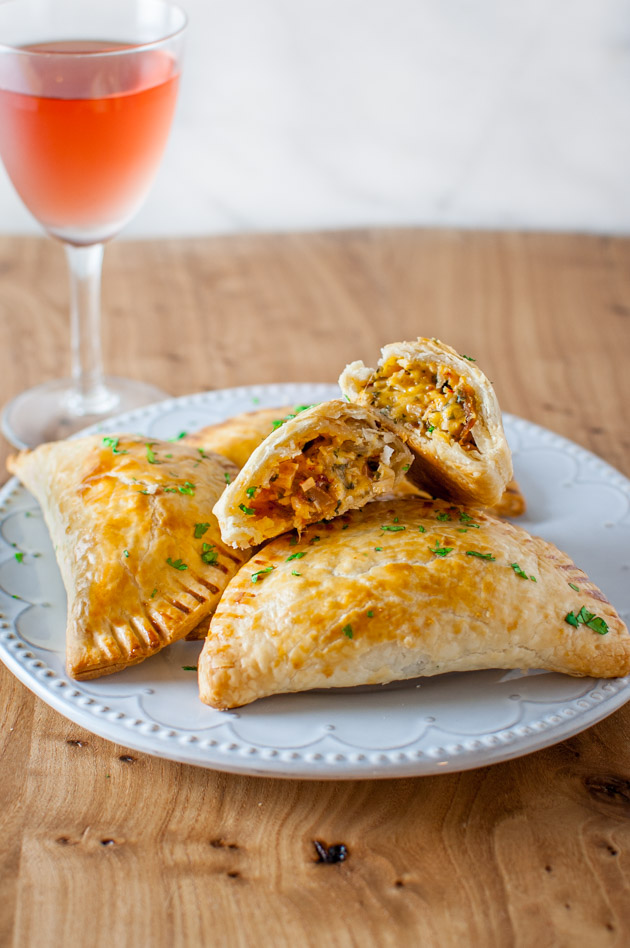 Turkey empanadas on a plate next to a glass wine.