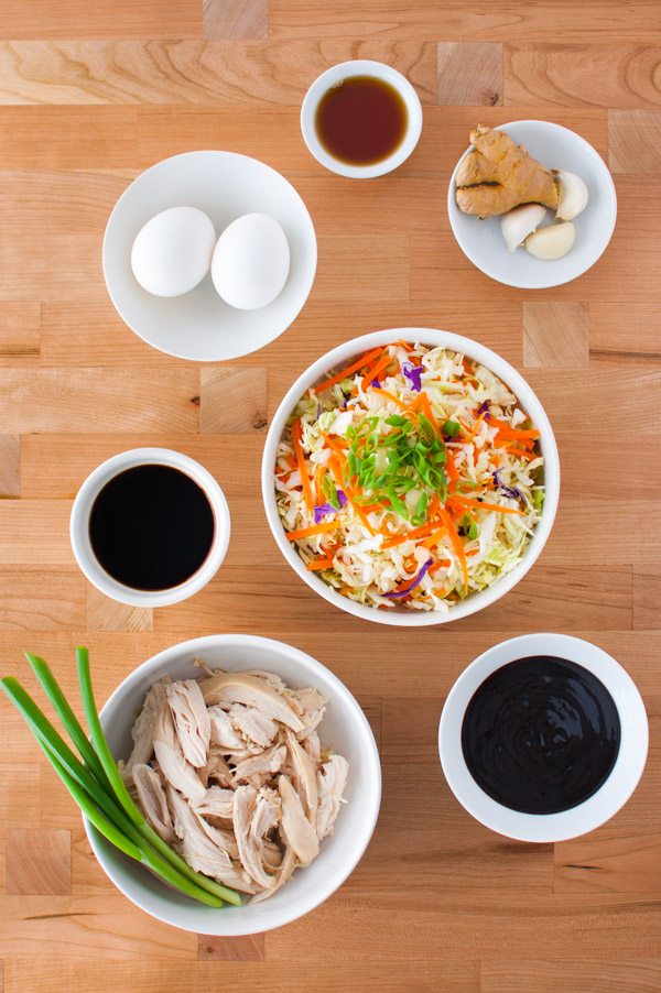 Ingredients for making mu shu chicken - eggs, garlic, hoisin sauce, shredded vegetables, and shredded chicken.