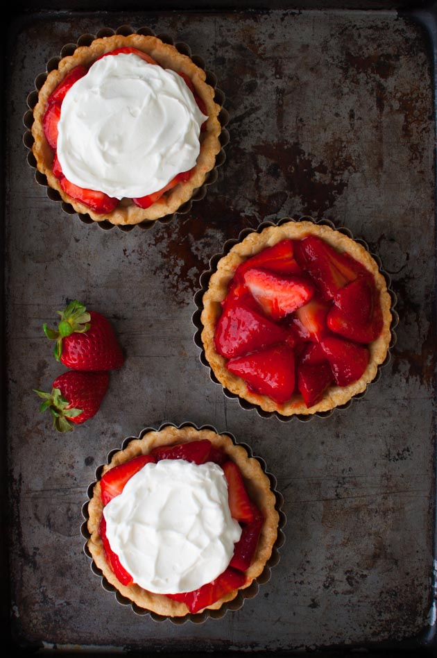Three mini fresh strawberry pies on a metal surface.