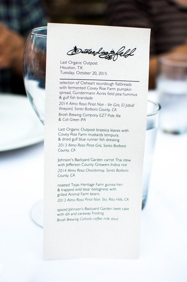 A printed menu standing in front of a wine glass.