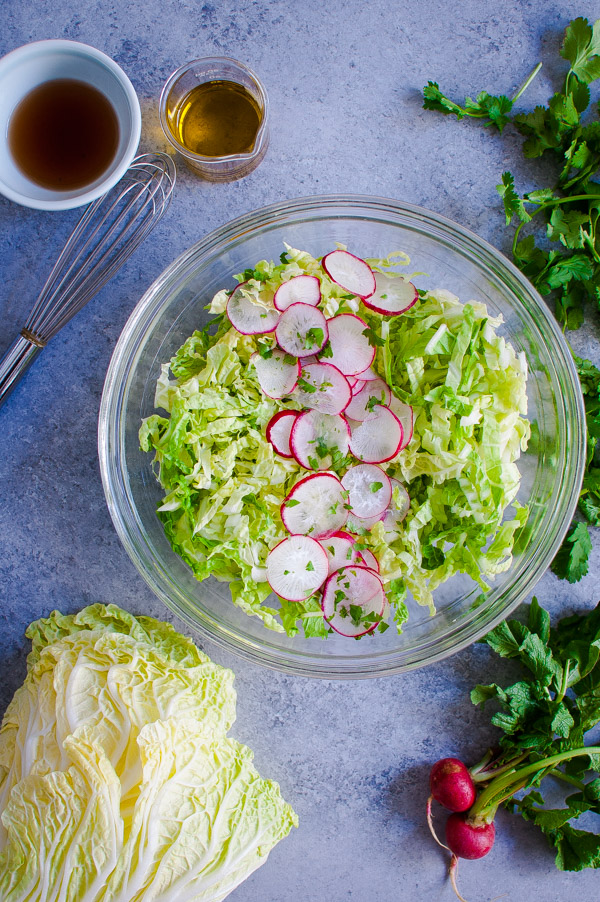 A bowl of slaw with napa cabbage and radishes.