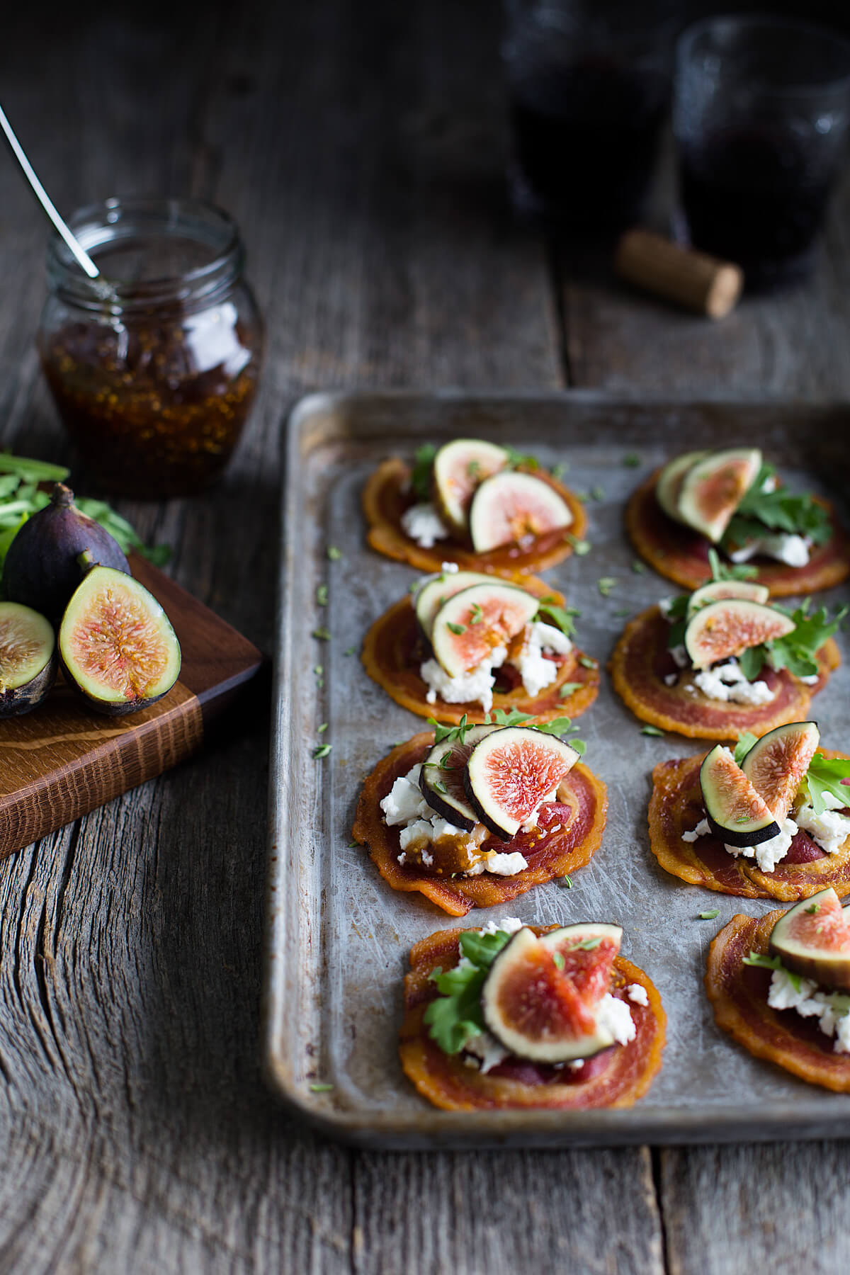 Tray of pancetta crisps topped with goat cheese, figs, and baby arugula.
