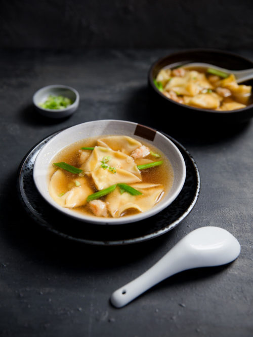 A bowl of shrimp dumpling soup topped with chopped green onions.