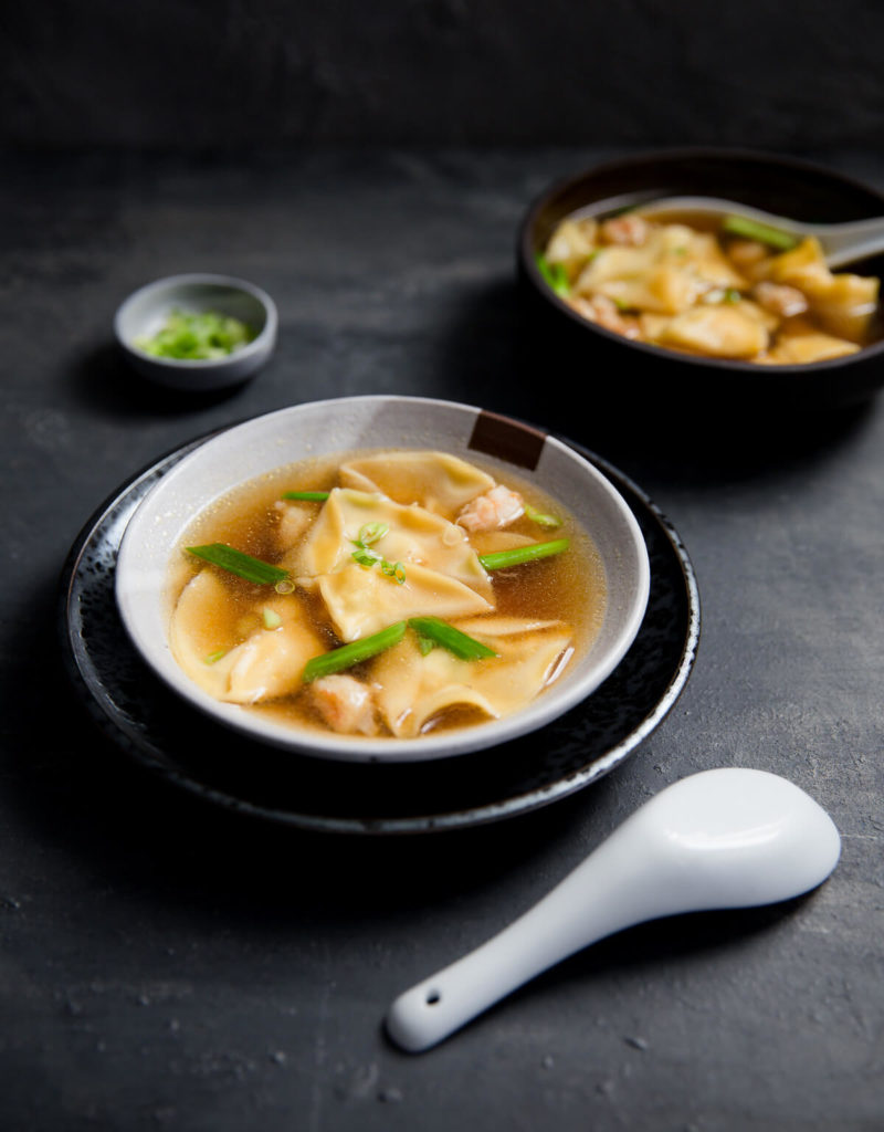 A bowl of shrimp dumpling soup topped with chopped green onions.