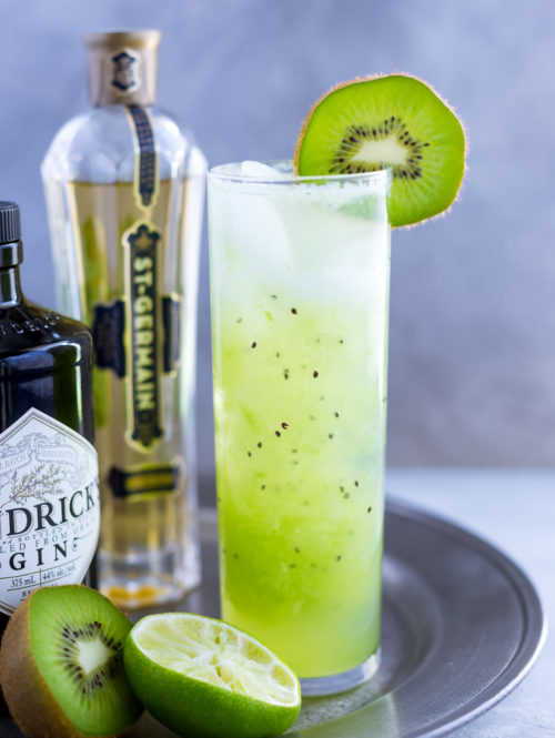 Kiwi cocktail in a tall garnished with a fresh kiwi slice.