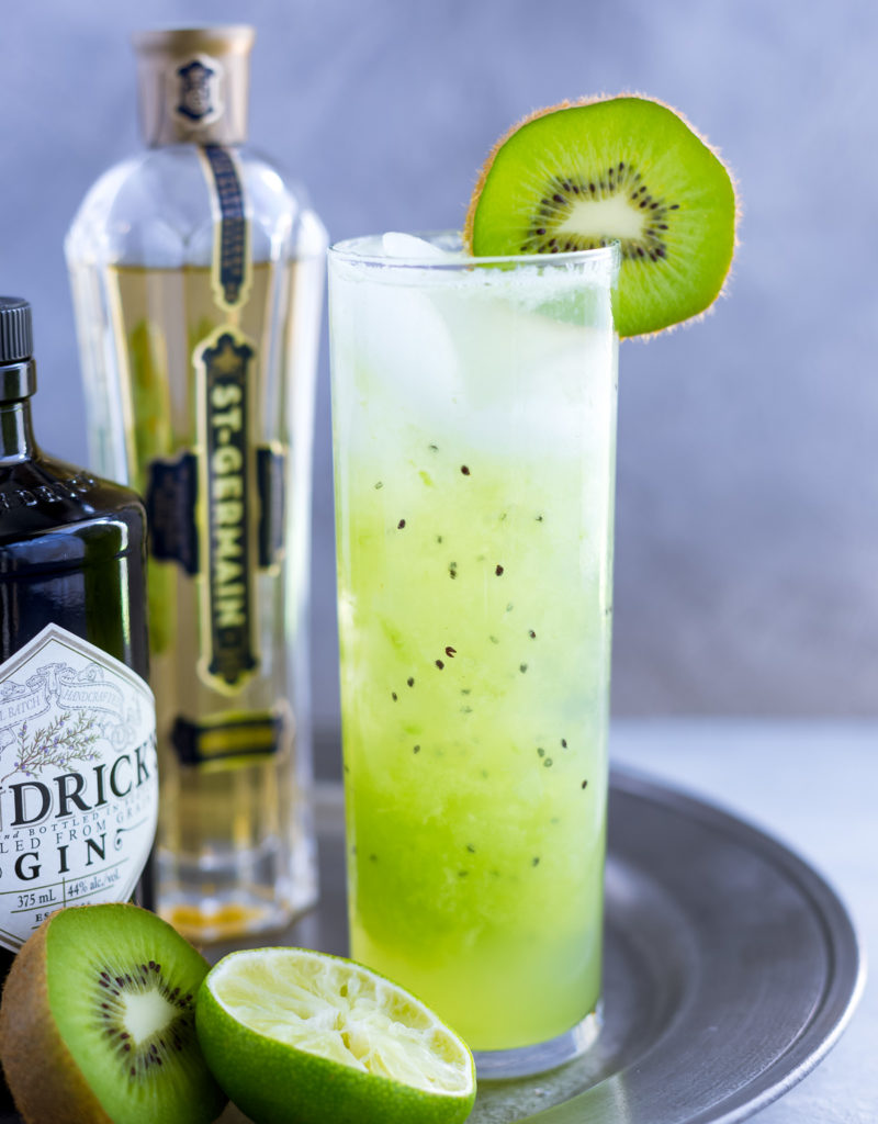 Kiwi cocktail in a tall garnished with a fresh kiwi slice.