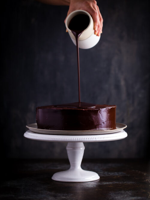 Chocolate ganache being poured on an inside-out German chocolate cake.