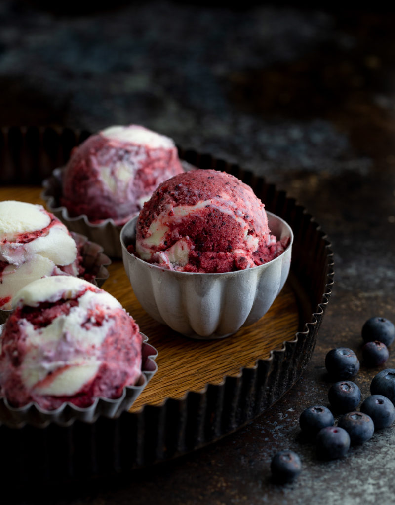 A scoop of blueberry sorbet vanilla ice-cream swirl in a metal cup.