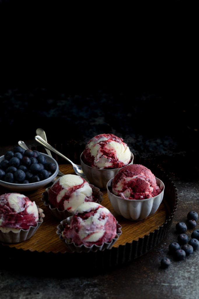Small bowls of blueberry sorbet vanilla ice-cream on a metal tray.