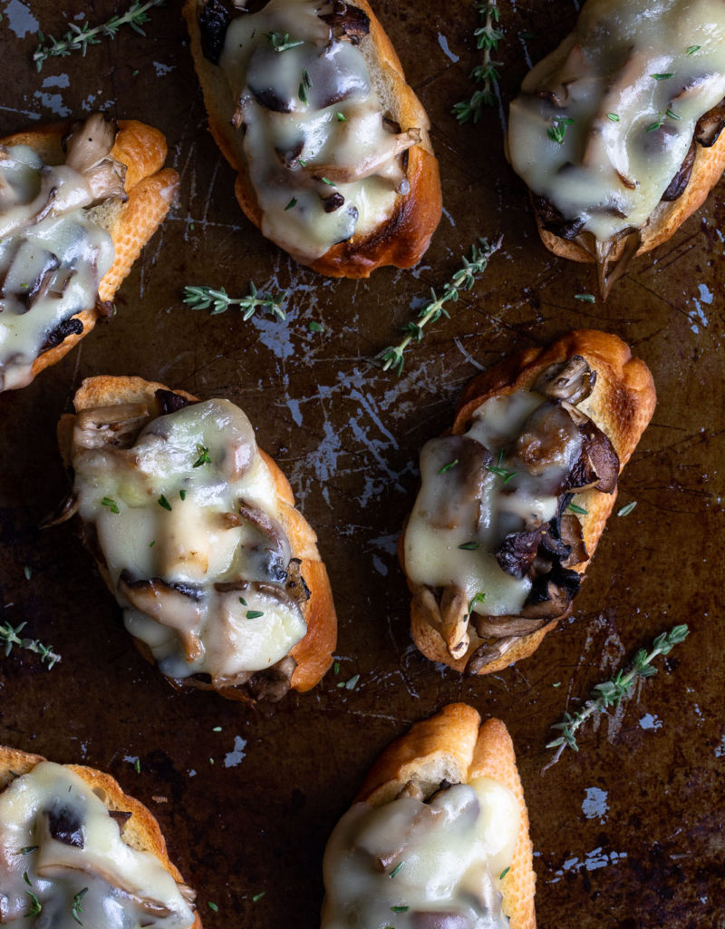 Roasted mushrooms and melted cheese on toasted bread slices.