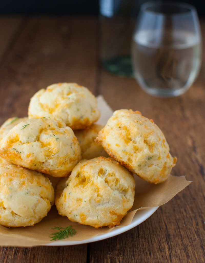 Plate of cheddar dill puffs on a wooden background.