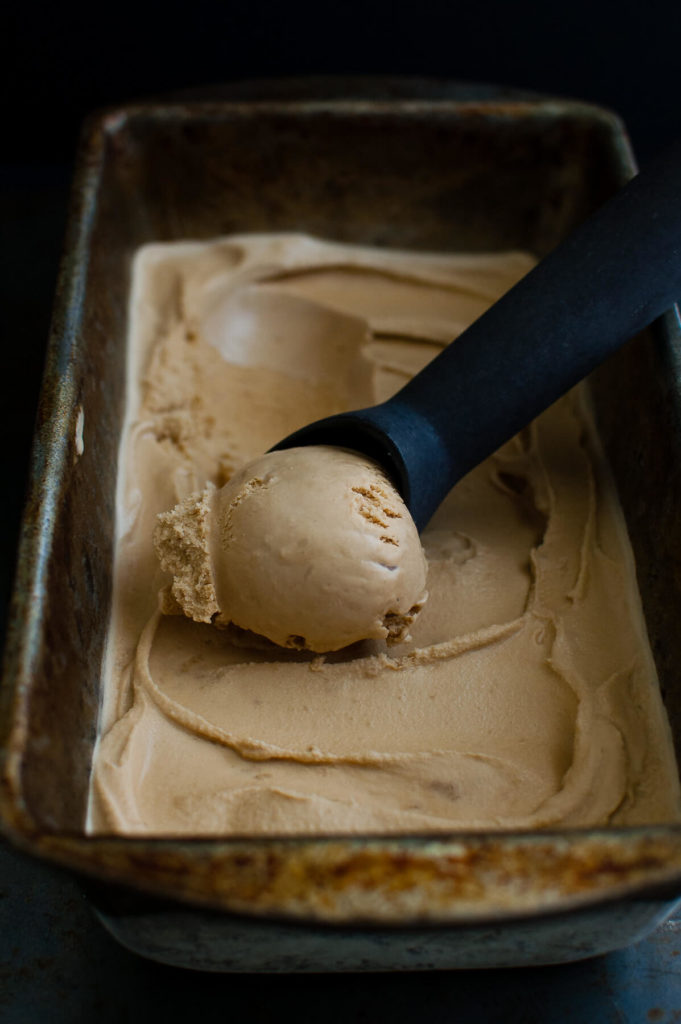 Vietnamese coffee ice-cream in a metal container with an ice-cream scoop.