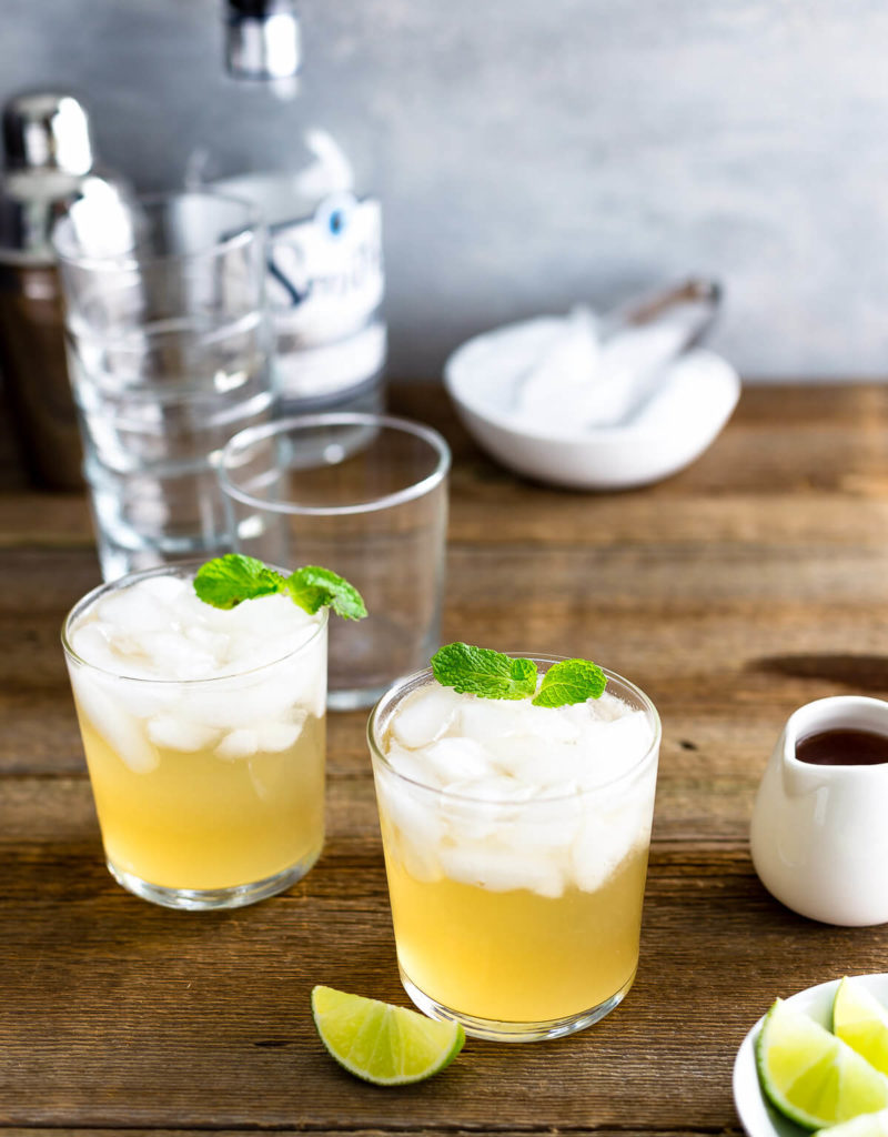 Two glasses of (Texas) Moscow Mule cocktail garnished with mint leaves on a dark wood table.