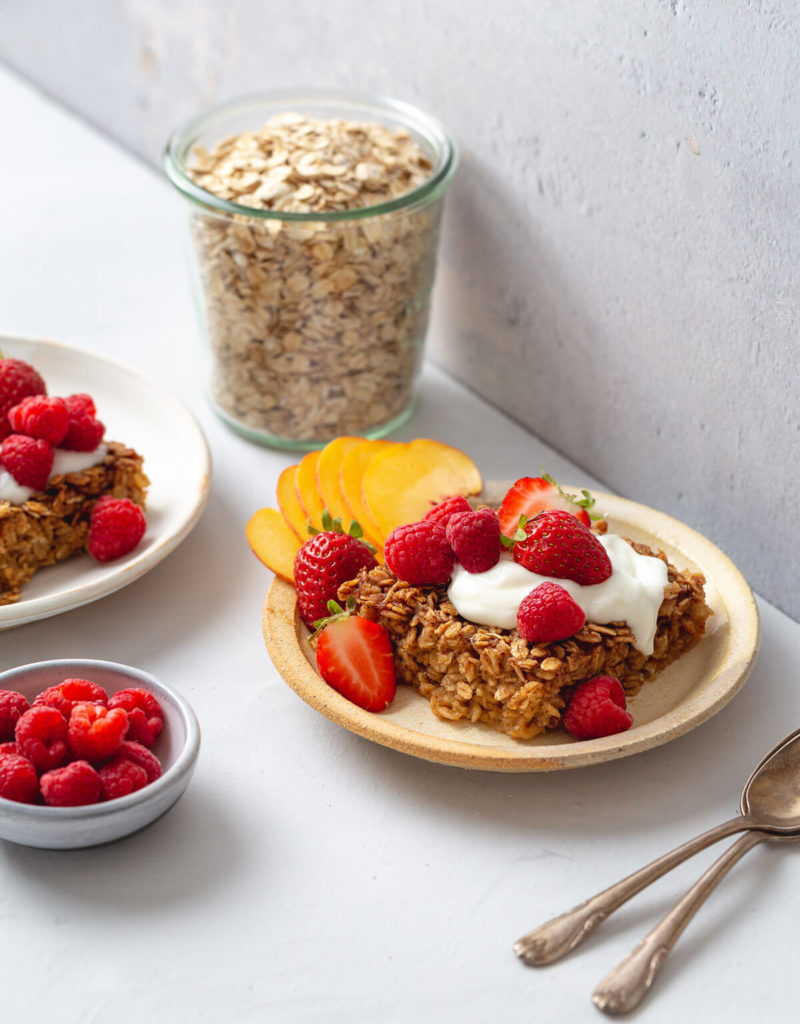 Plate of baked oatmeal topped with yogurt and fresh fruit.