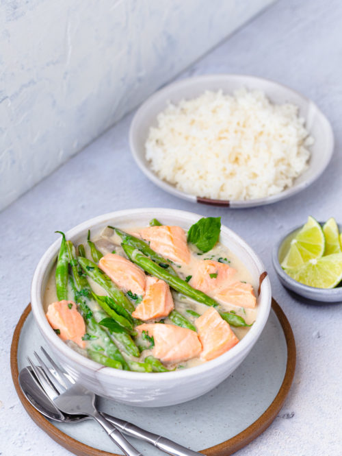 Bowl of salmon in coconut-miso broth with green beans served with a bowl of rice.