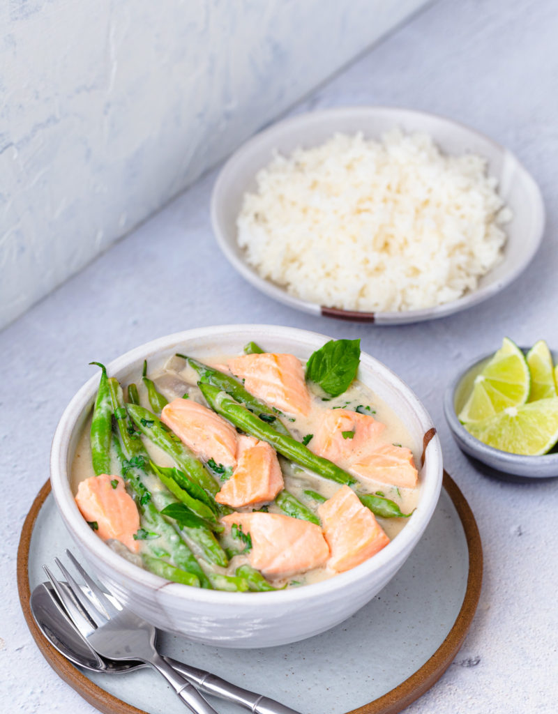Bowl of salmon in coconut-miso broth with green beans served with a bowl of rice.