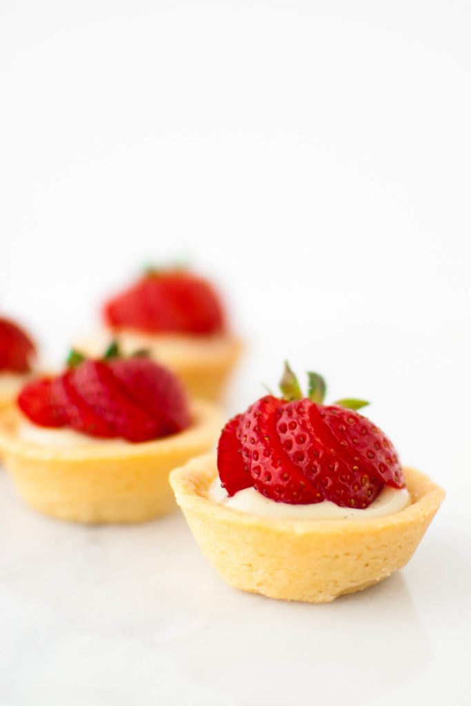 A close-up shot of mini fruit tartlets with vanilla pastry cream and strawberries.