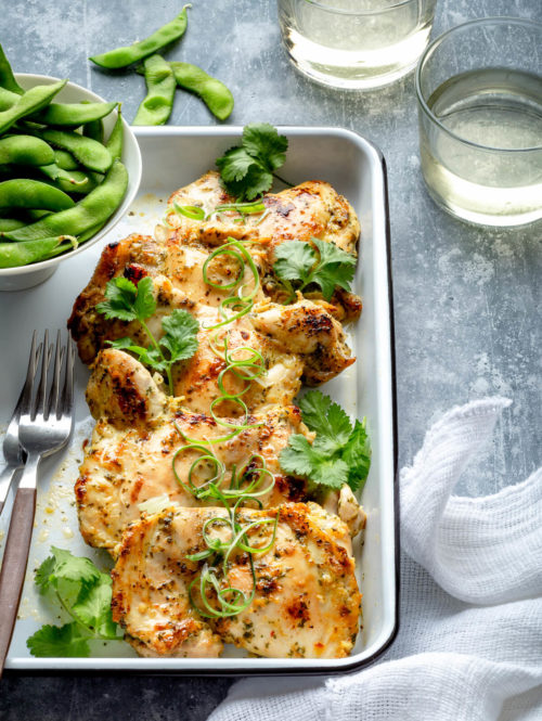 A white tray with some cilantro lime chicken and edamame.