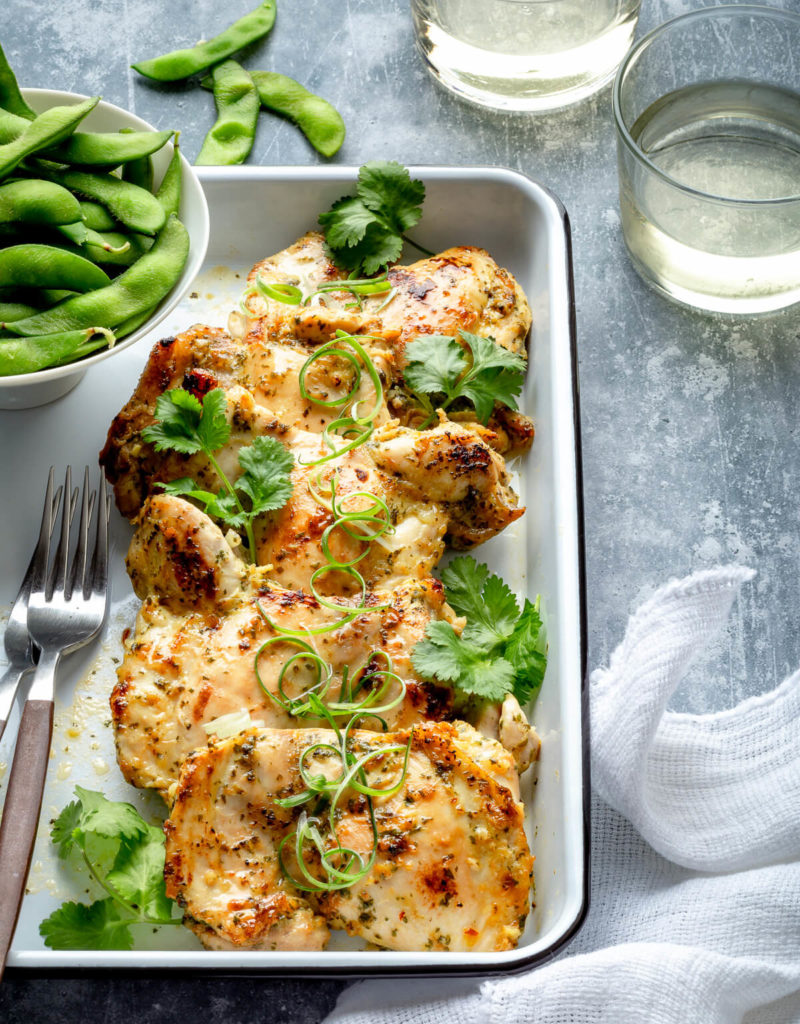 A white tray with some cilantro lime chicken and edamame.