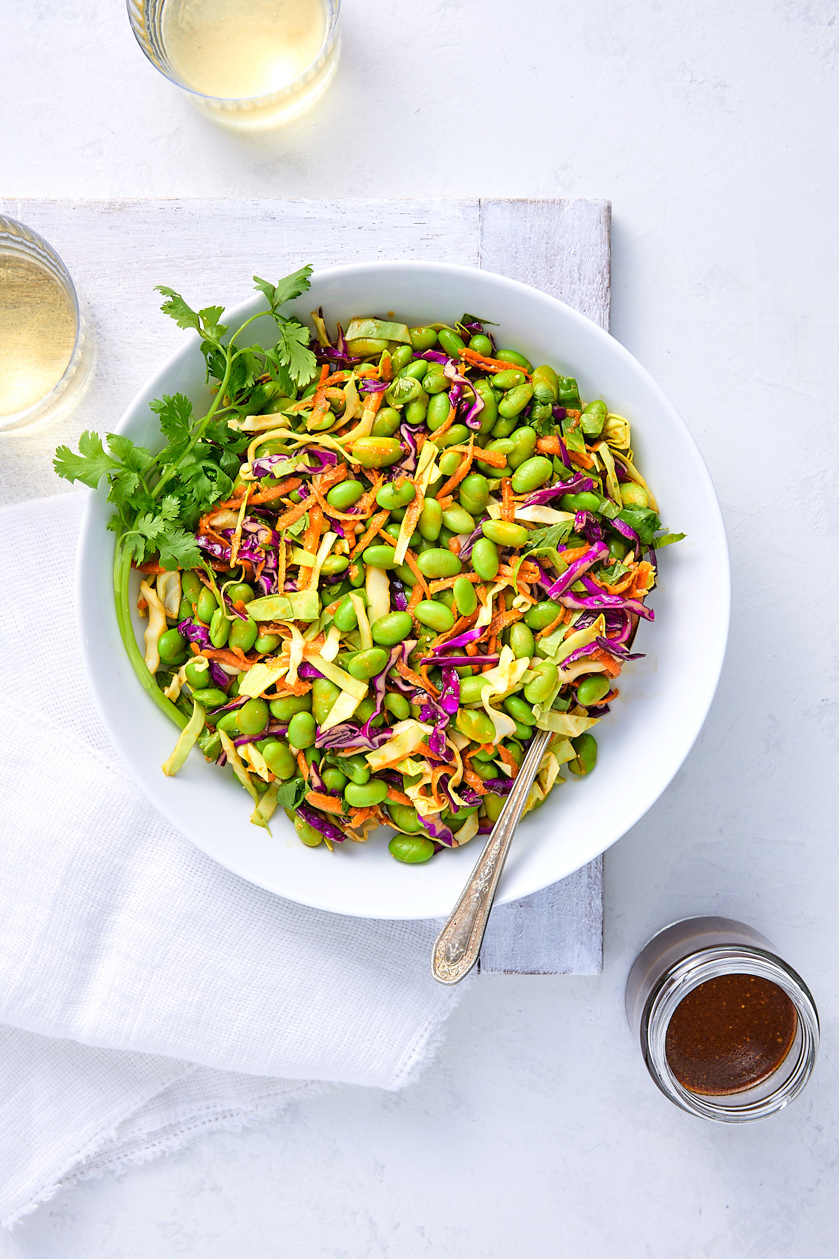 Big bowl of edamame salad with jar of miso dressing.