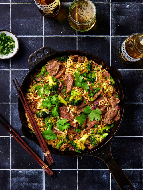Top down view of skillet with beef noodles and broccoli.