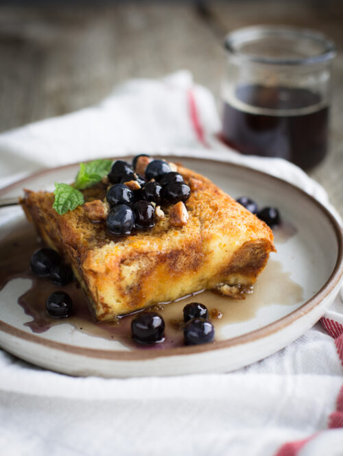 Baked brioche french toast topped with maple syrup and blueberries.