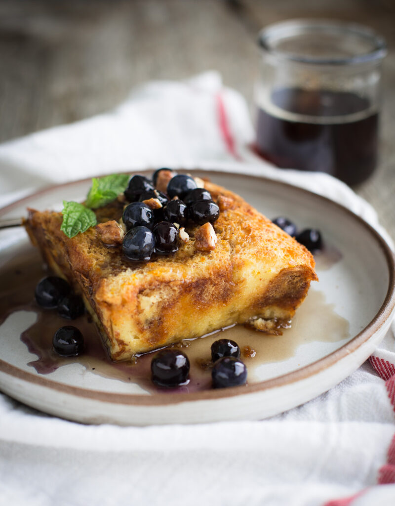 Baked brioche french toast topped with maple syrup and blueberries.