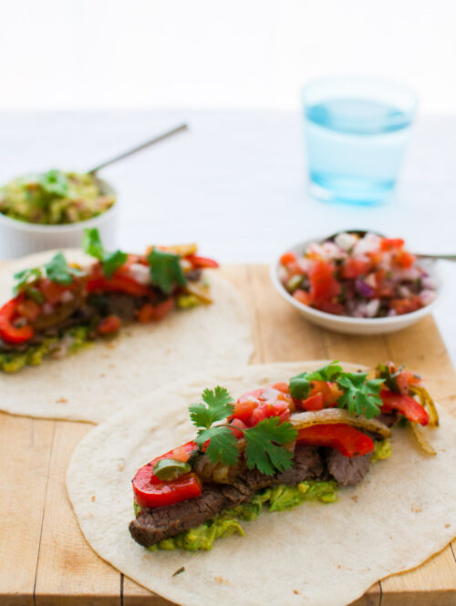 Beef fajitas served on a wooden board.