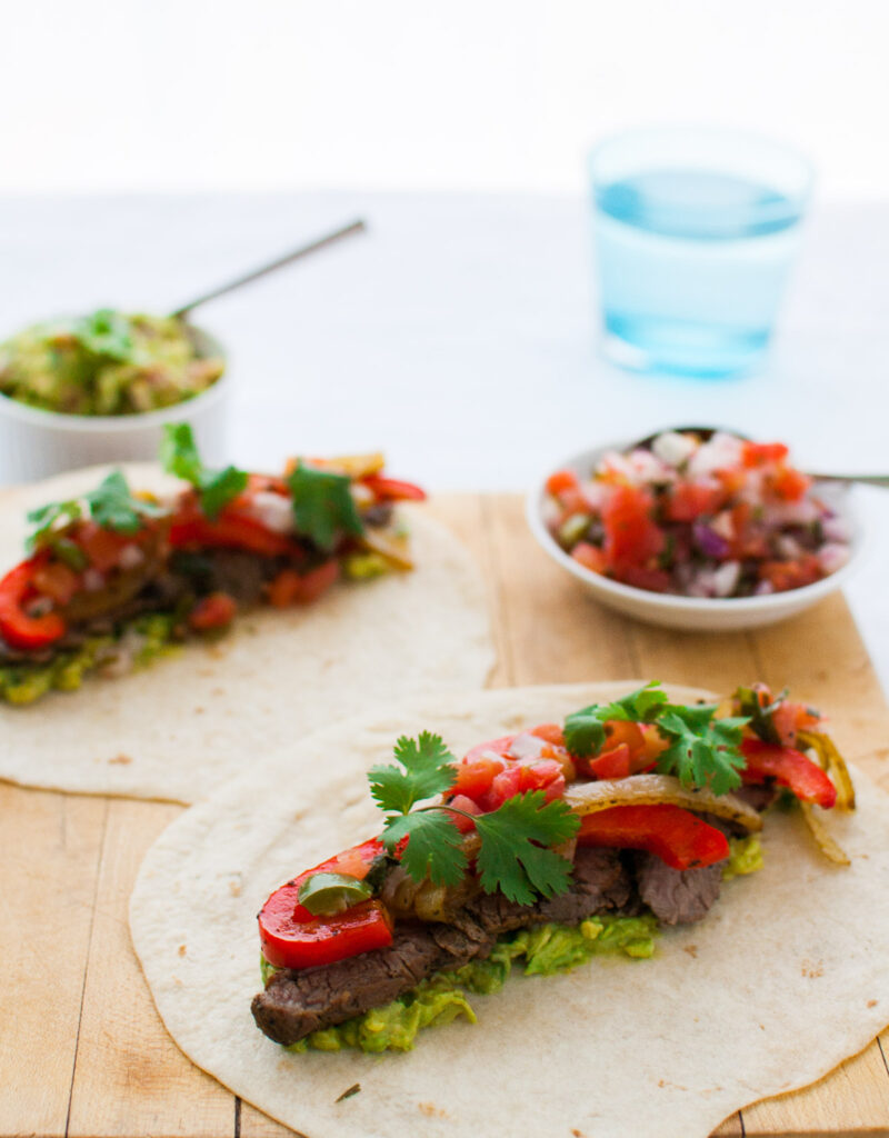 Beef fajitas served on a wooden board.