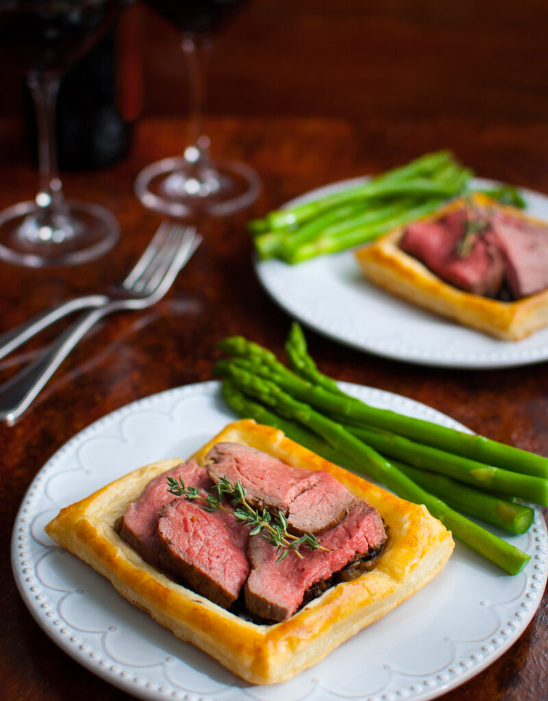 Beef Wellington tarts served with asparagus.