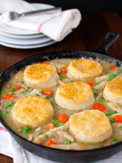 Chicken pot pie topped with biscuits in a cast iron skillet.
