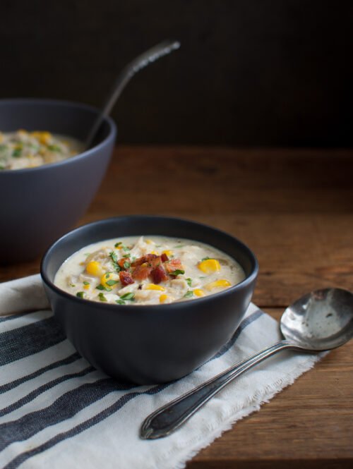 A bowl of crab and corn chowder in a black bowl.