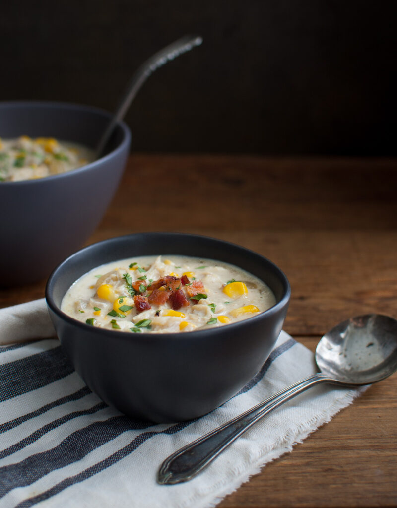 A bowl of crab and corn chowder in a black bowl.