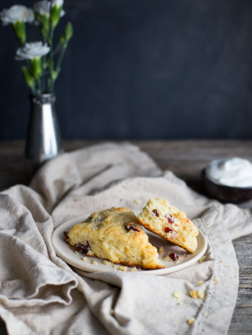 Two cranberry orange scones on a white plate with a linen napkin.