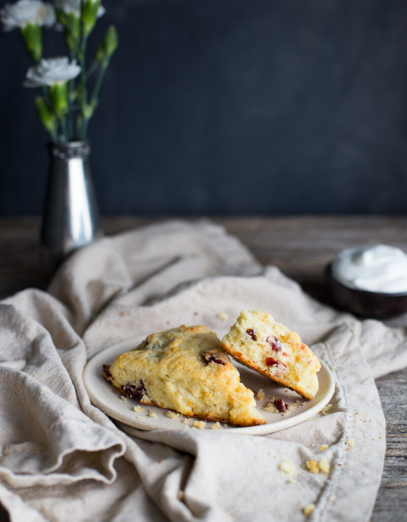 Two cranberry orange scones on a white plate with a linen napkin.