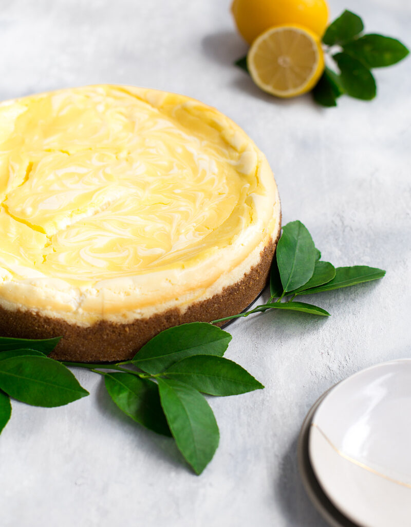 A lemon curd marbled cheesecake garnished with lemon leaves.