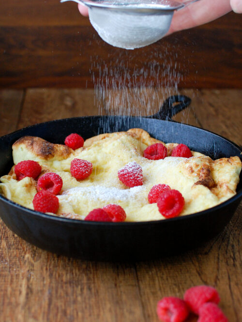 Pear dutch baby sprinkled with powdered sugar.