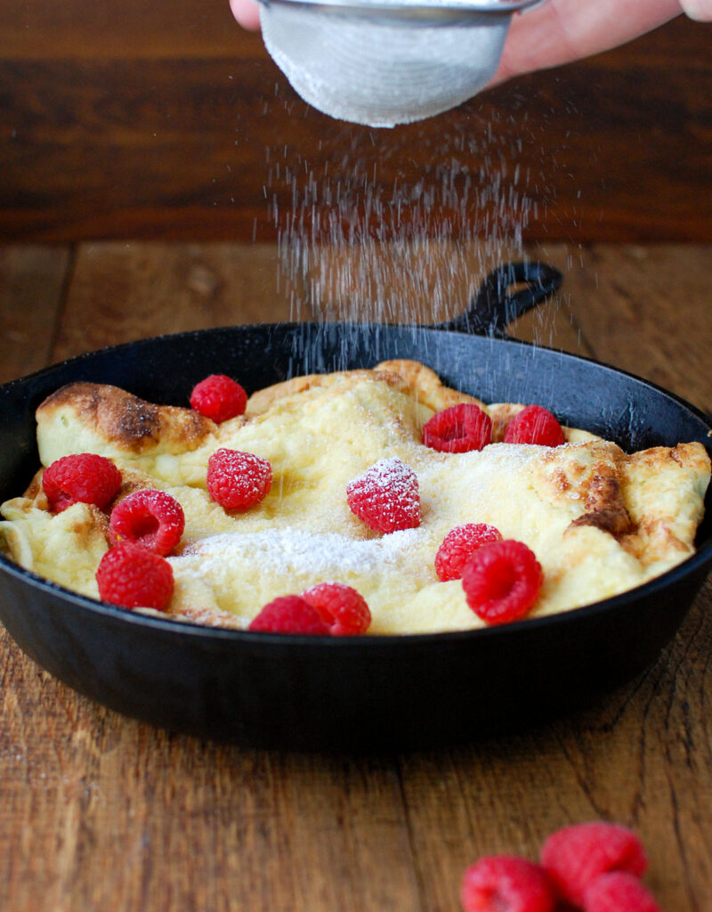 Pear dutch baby sprinkled with powdered sugar.