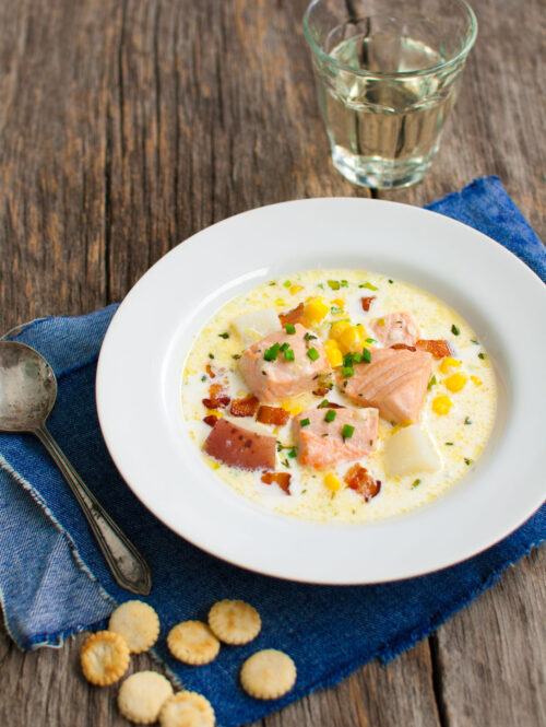 Bowl of salmon chowder served on a blue napkin.
