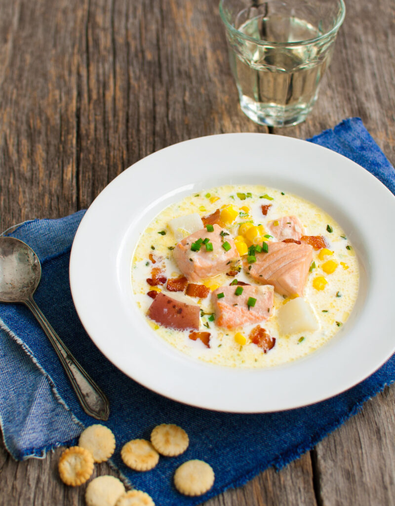 Bowl of salmon chowder served on a blue napkin.