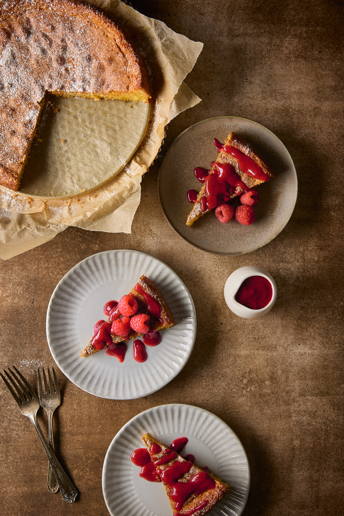 Three plates with slices of almond torte with raspberry sauce.