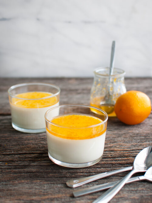Lemon panna cotta topped with sweet meyer lemon marmalade in two glass dessert cups.