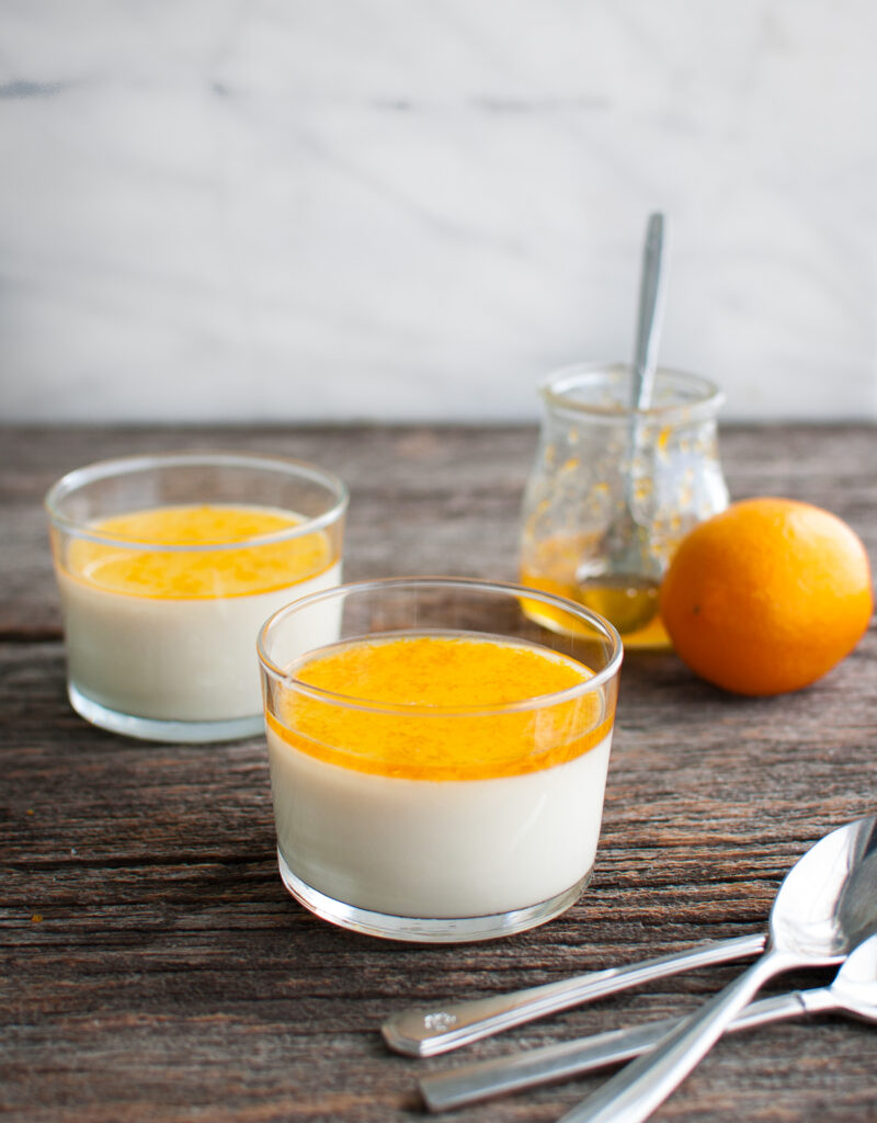 Lemon panna cotta topped with sweet meyer lemon marmalade in two glass dessert cups.